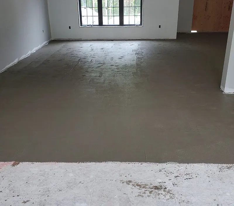 Room with a fresh scratch coat of mortar over metal lath on the subfloor, the lath pattern still showing, a strip of bare subfloor in front